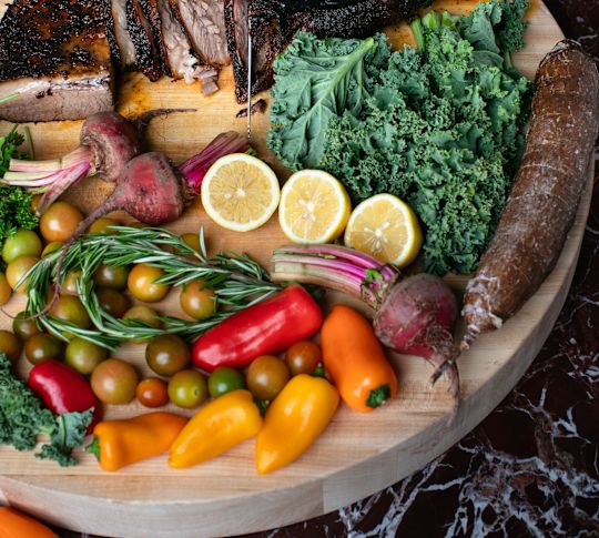 Chef Slicing Meat on a Wooden Tray with Vegetables