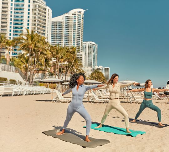 Femei exersând yoga la plajă
