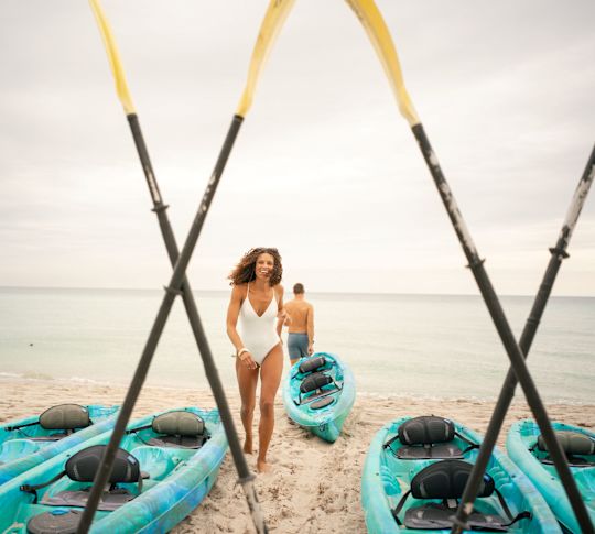 Cuplu pe plajă cu oaspetele Kayaks aliniat