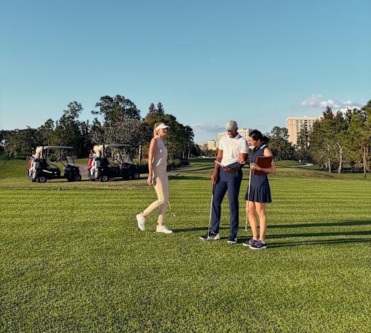Un homme et deux femmes sur un parcours en or, avec des poussettes en arrière-plan