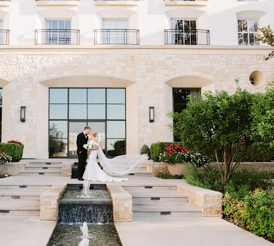 Bride and Groom  Kissing on Hotel Exterior Entrance with  Decorative Fountains-transition