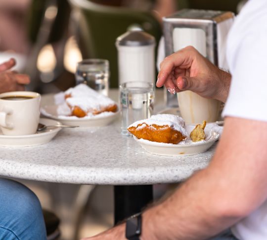 Due persone che amano i beignet ricoperti di zucchero in polvere.