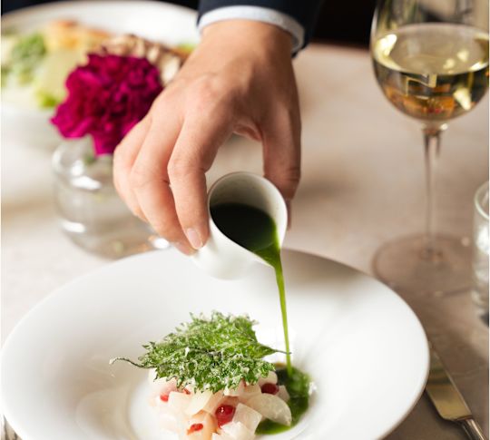 Bedienend personeel dat saus op een bord schenkt bij Brasserie Goldfinch-transition