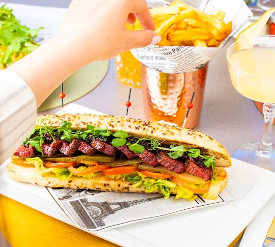 Žena večeřící sendvič a hranolky v Jardin du Trianon