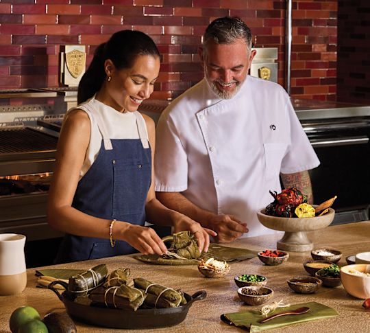 Femme souriante tandis que le chef enseigne en cours de cuisine