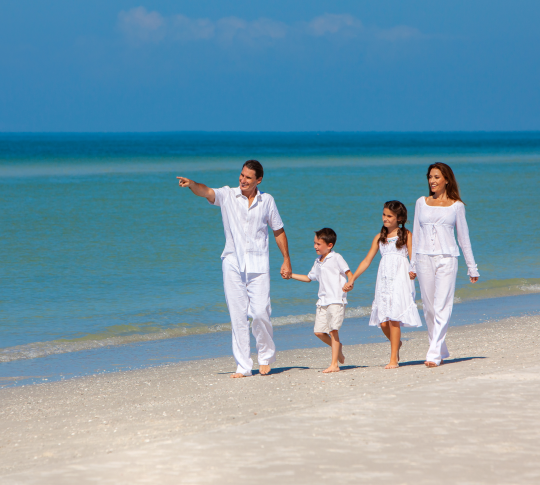 Family all dressed in white walking down beach