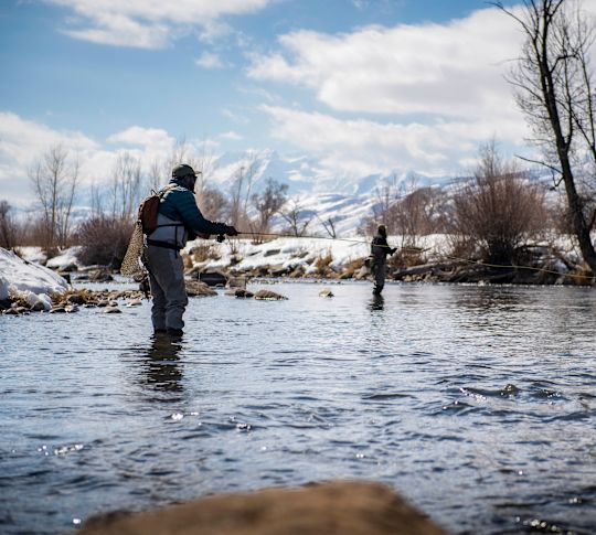 Oameni care zboarăPescuit într-o zonă cu zăpadă și munți
