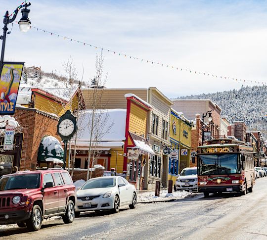 People Walking on Busy Main Street In a City with Mountains in Background