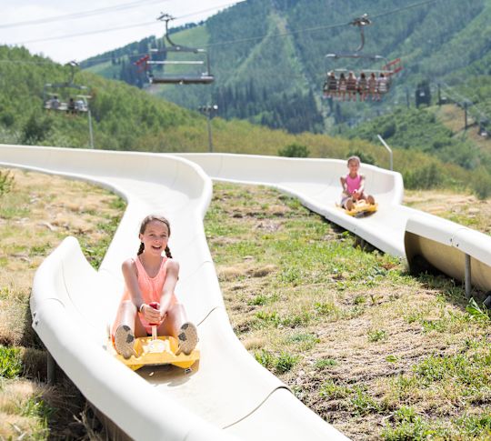 Two girls coming down the alpine slide.