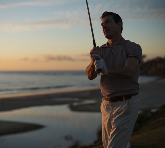 a man playing golf at sunset
