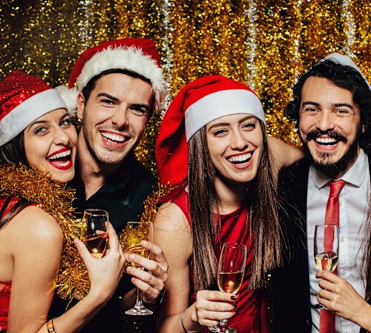 men and women smiling wearing santa hats