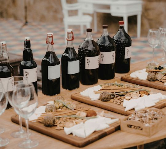 Bottles of wine set up in a row with wine glasses and meat, nuts and cheese boards ready for guests participating in a wine tour.