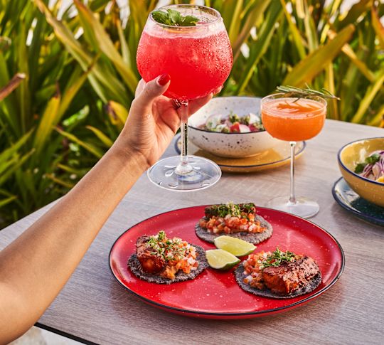 Cocktail in hand and plate with food