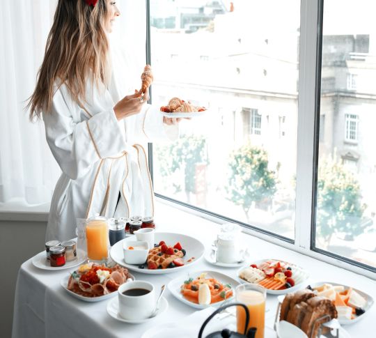 Woman looking outside with breakfast spread on table