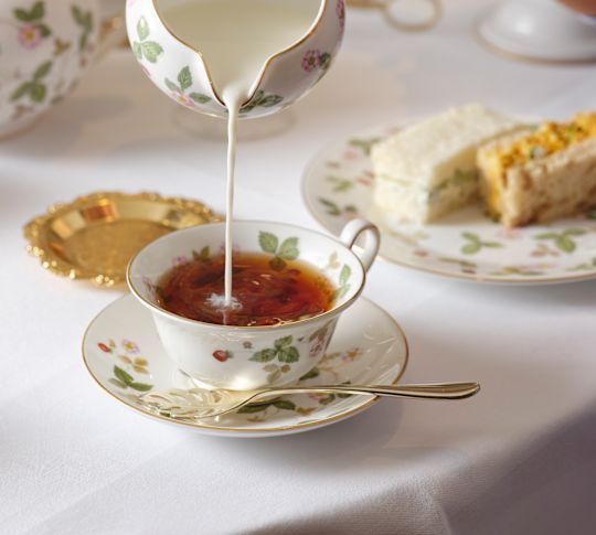 Woman Pouring Cream on a Cup for Tea Time at The Orchard Room