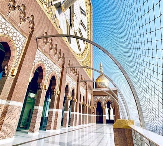 Brick building with gold accents, arches and a large clock.