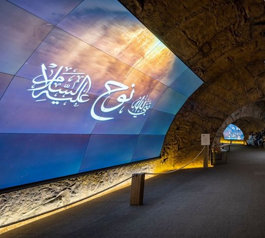 Tunnel in the dark with Arabic writing on the wall.
