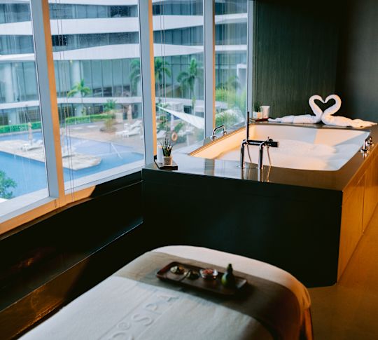 Łóżko do masażu z produktami leczniczymi i wanną w spa z widokiem na basen