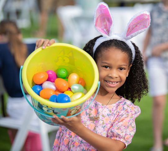 niña pequeña sosteniendo un cubo lleno de huevos de Pascua