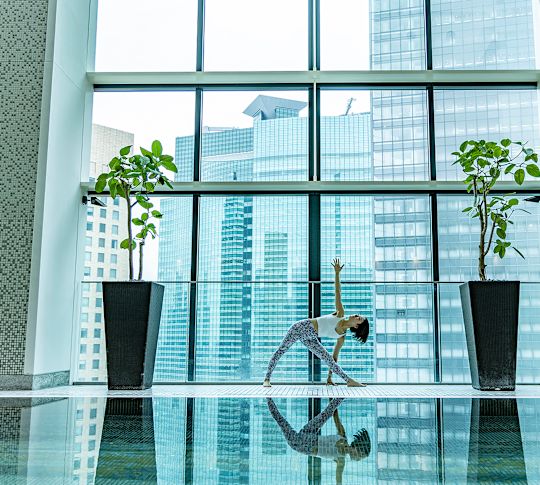 Frau beim Yoga vor dem großen Fenster