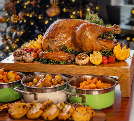 roasted turkey, bowls of vegetables, holiday tree in the background