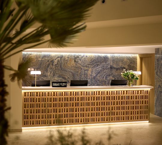 Empfangsbereich mit Pflanzen und Hilton-Beschilderung