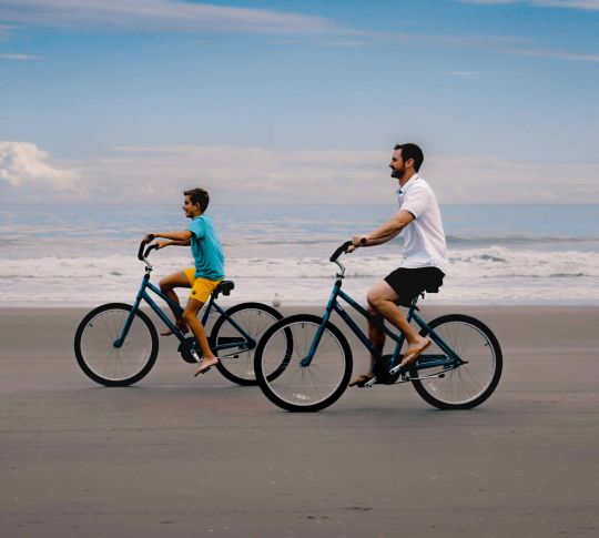Dad and son biking on the beach