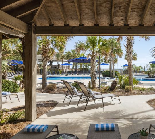 Beautiful outdoor cabana area featuring ample seating for guests and view of pool.