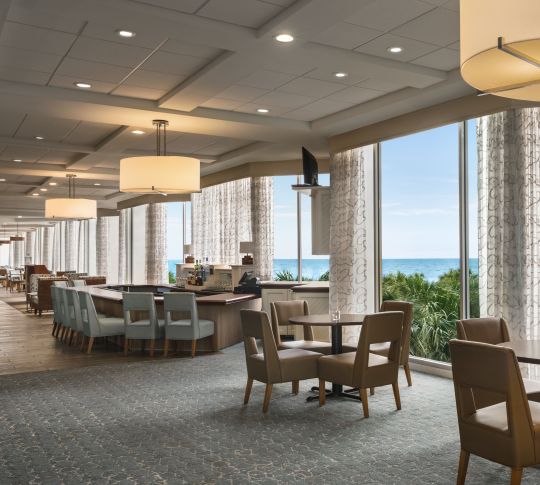 Spacieux espace bar intérieur avec baies vitrées donnant sur l'océan.