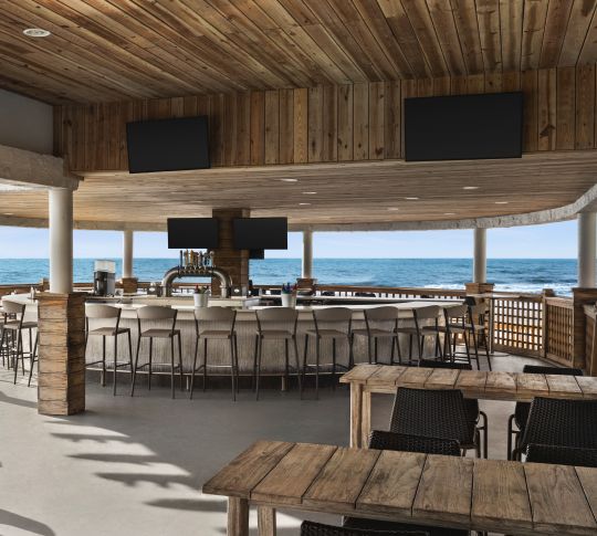 Spacious outdoor bar featuring ample seating and stunning ocean view.