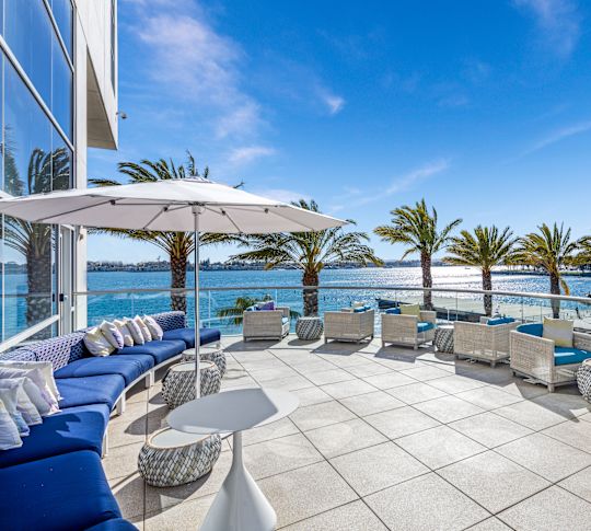 Odysea restaurant terrace, lounge chairs, umbrella, palm trees, view of the ocean