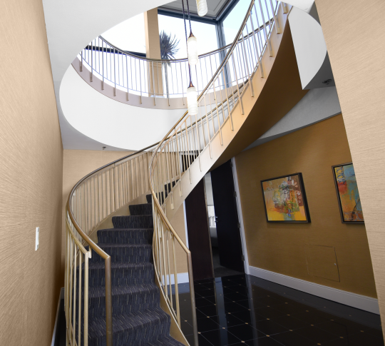 Elliptical staircase with gold-tone rails in the two bedroom suite.