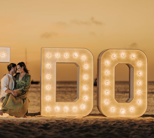 Couple in front of 'I Do' light up sign on the beach