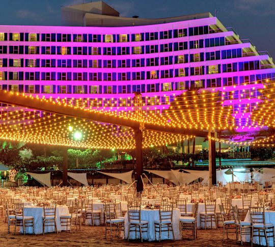 Outdoor party set up with tables and pink hued lights