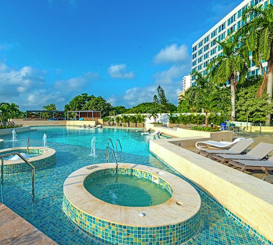 Pool area with hot tubs and lounge chairs