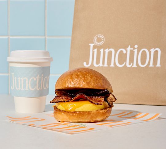 Junction brown bag with coffee and breakfast sandwich on table