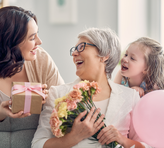 woman holding flowers laughing with woman and little girl