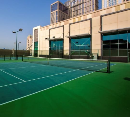 Exterior tennis court with hotel building in background