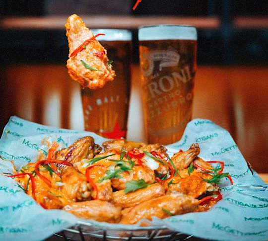 Ailes de poulet sur un panier et bières sur une table à l'usine McGettigans