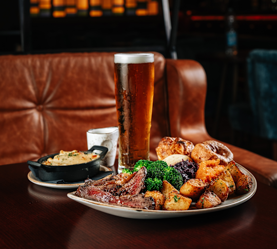 Rôtissez avec des pommes de terre et des brocolis sur une assiette, et un verre de bière à l'usine McGettigans