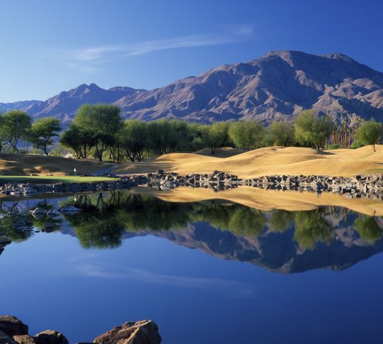 Panoramic view over a lake with mountains in the background. Location is TPC Stadium Course at PGA WEST