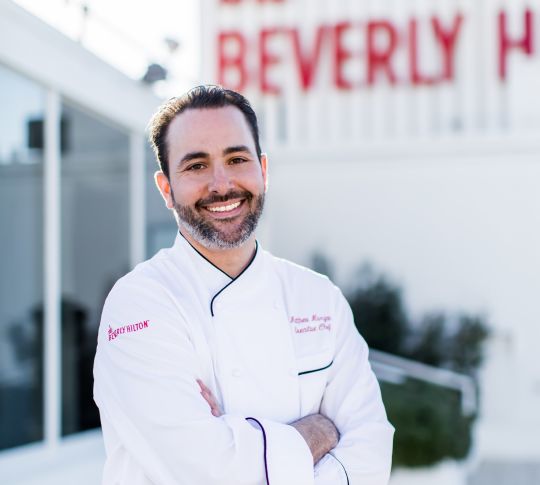 Team member photograph, featuring chef in whites standing outside restaurant