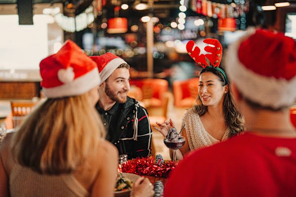 4 people wearing christmas hats sitting round a table