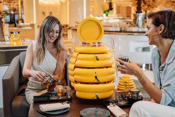 two women at a table with a large honey comb cabinet