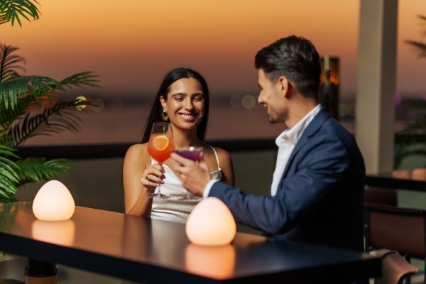 couple toasting drinks at outdoor bar at dusk