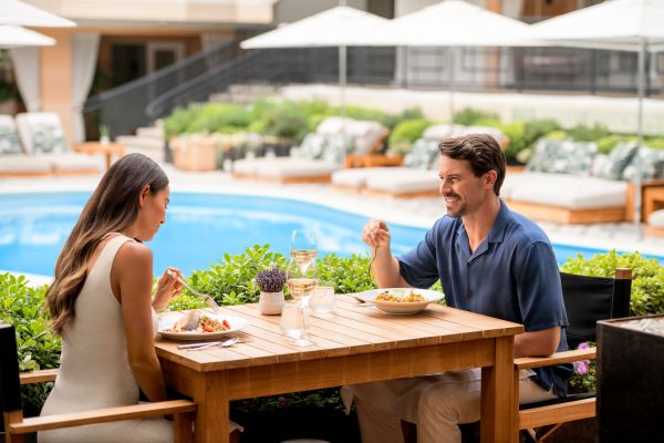 Couple sitting at table eating meal next to pool