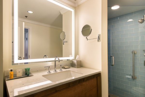 Accessible bathroom with roll-in shower, handrail, vanity mirror with sink and bathroom amenities
