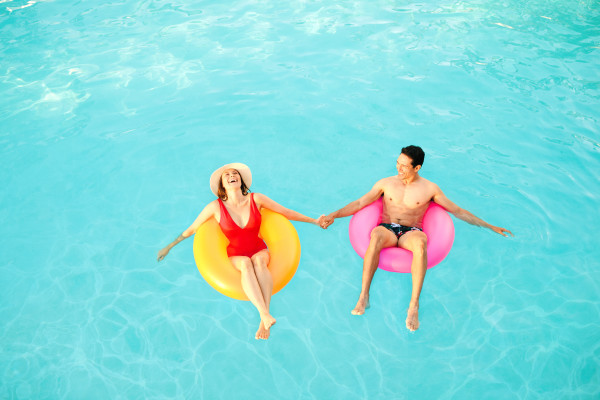 Man and woman in pool, floating on rubber rings