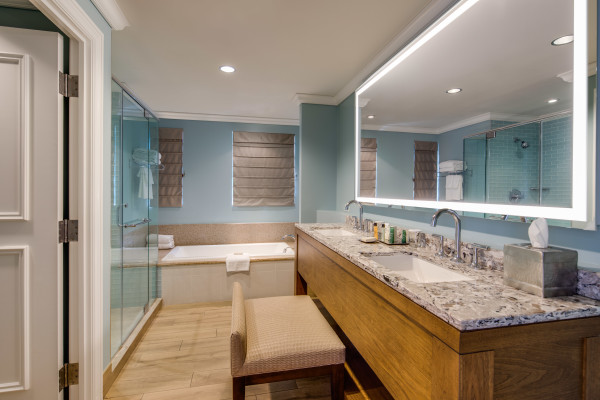 King suite bathroom with large vanity mirror, two sinks, tub, and shower