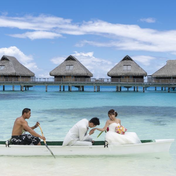 People on boat with floating villas in background